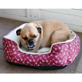Dog lying on a red and white patterned pet bed indoors.
