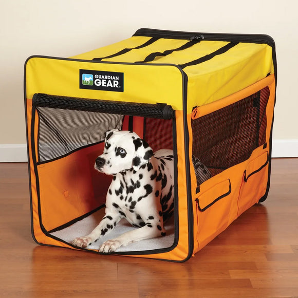 Dog inside a yellow and orange Guardian Gear pet crate on a wooden floor.