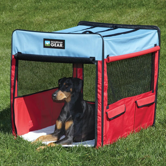 Dog lying inside a red and blue portable pet pen on grass