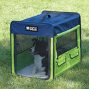 Green and blue pet crate with a dog inside on grass
