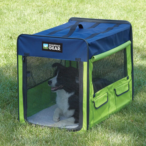 Green and blue pet crate with a dog inside on grass