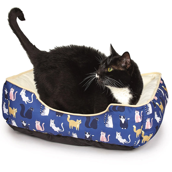 Black cat sitting on a blue pet bed with cat pattern