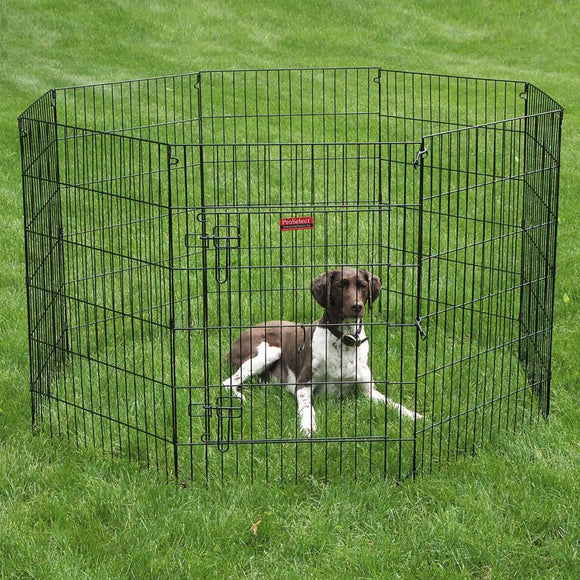 Dog inside a black metal pet playpen on grass