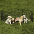 Three dogs inside a black metal dog pen on grass