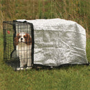 Dog in a crate with a cover in a grassy outdoor setting