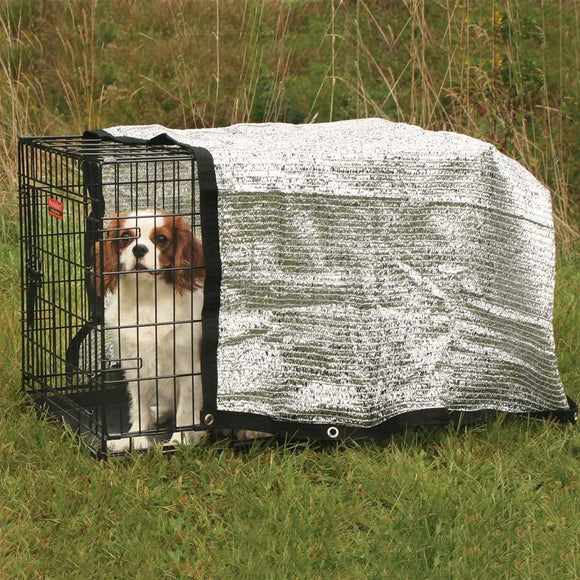 Dog in a crate with a cover in a grassy outdoor setting