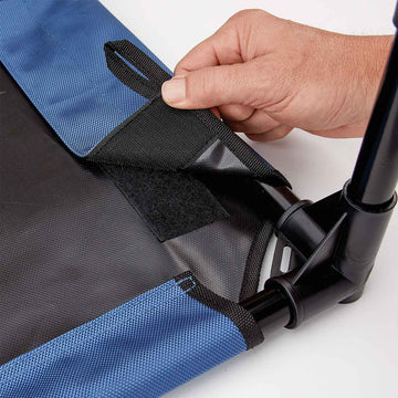 Hand adjusting a black strap on a blue and gray bag against a white background