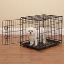 Dog inside a black metal crate on a wooden floor.