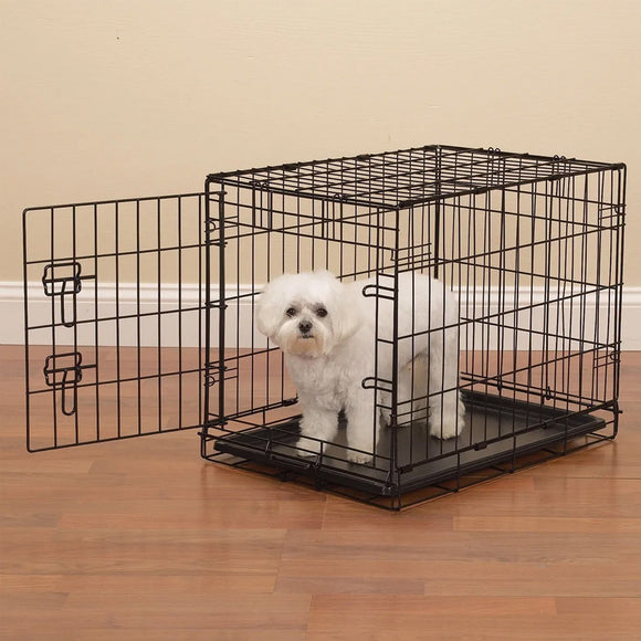 Dog inside a black metal crate on a wooden floor.