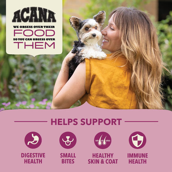 Woman holding a small dog with Acana pet food advertisement in the background