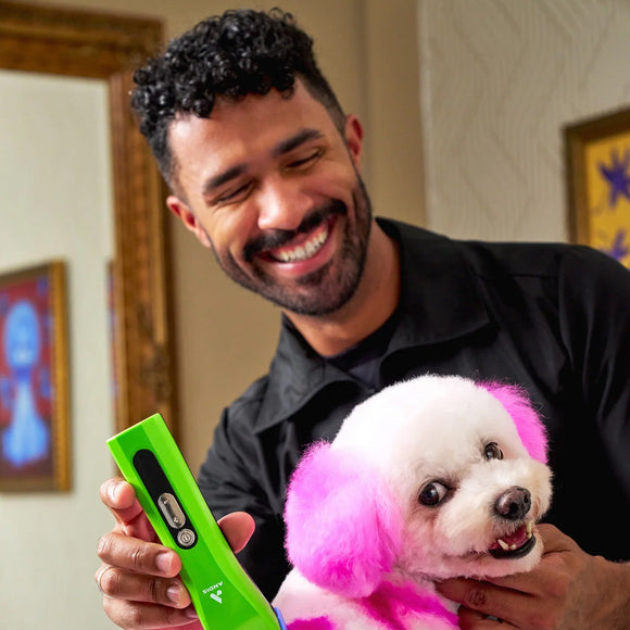 Man holding a dog with pink fur and a green device in a room.