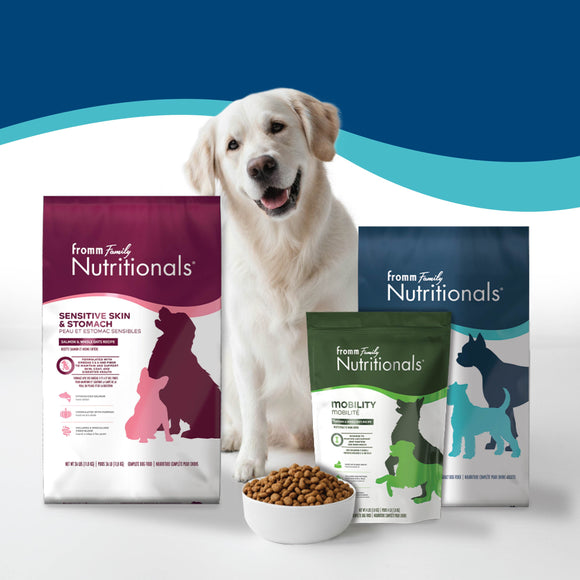 Dog with Fromm Family Nutritionals dog food packages on a white background