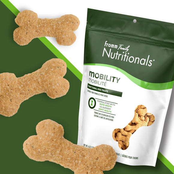 Dog treats shaped like bones with a 'fromm family nutritionals' package on a green background