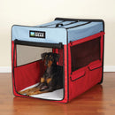 Red and blue pet crate with a dog inside on a wooden floor.