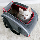 Small white dog peeking out from a gray pet carrier with red interior on a light carpet.