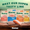 Natoo pet food packages on a wooden surface with salmon fillets, against a scenic background.