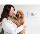 Woman holding a brown dog with a photo frame in the background