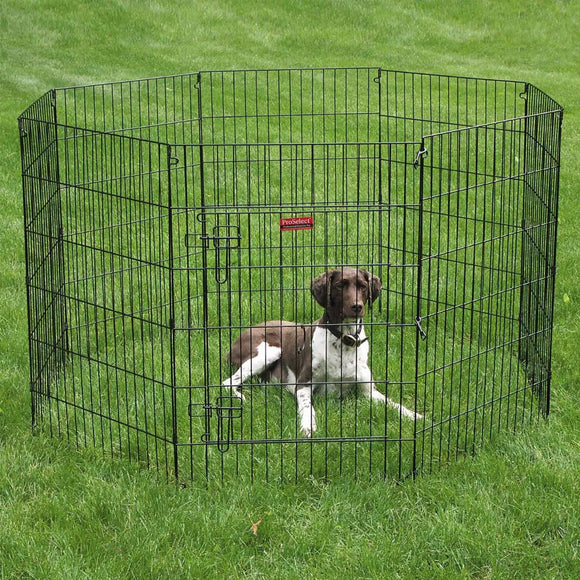 Dog inside a black metal pet playpen on grass