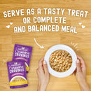 Stella & Chewy's Carnivore Cravings pet food packages with a bowl of food on a wooden surface.