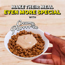 Hand holding a bowl of dog food with creamy purrree on a wooden surface