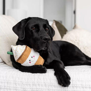Black dog lying on a couch with a snowman-shaped toy