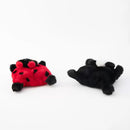 Two plush toys, one red and black ladybug and one black spider, on a white background.